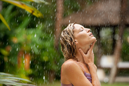 根据热带雨在异国情调的花园中有吸引力的女人