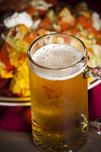食品和饮料。与一盘辣玉米片冷 冷淡杯啤酒一个特写图像