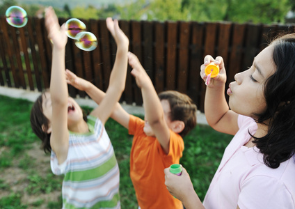 快乐的孩子们在玩户外的泡沫，选择性焦点孩子在运动中