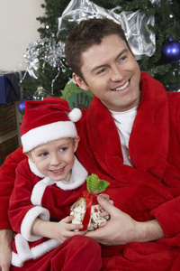 父亲和儿子在圣诞老人衣服持有本