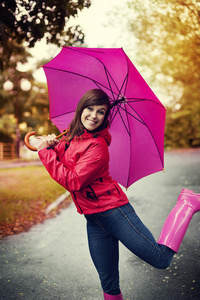 年轻女子在粉红色的雨伞下