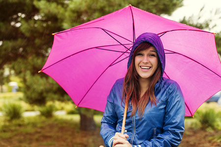 年轻女子在粉红色的雨伞下