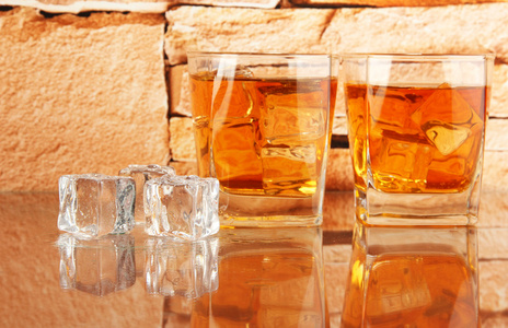 杯威士忌和砖上的冰墙背景