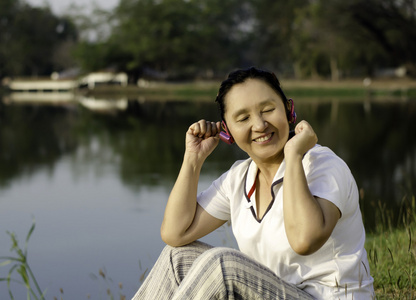 漂亮的亚洲女子在封闭的耳机听音乐
