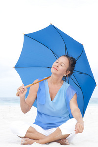 轻松成熟的女人蓝伞海滩