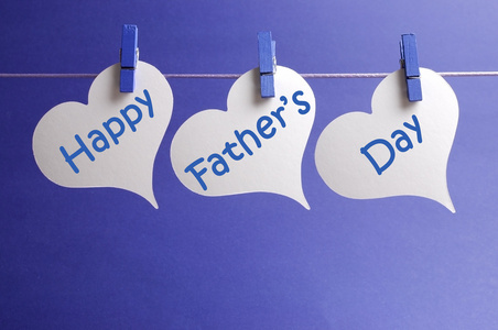 快乐的父亲一天消息写在白心形状标签挂在蓝钉上一线蓝色的背景上