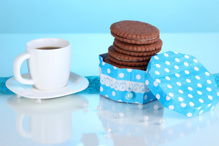 与奶油层和杯咖啡在蓝色背景上的巧克力饼干