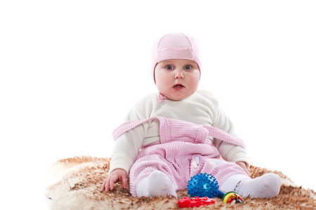 坐在一块毛皮地毯与玩具上的小女孩