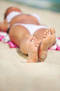 在海滩上晒黑的美丽双腿的女人
