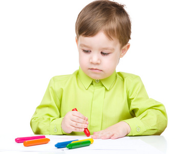 小男孩绘图使用蜡笔的白色纸上