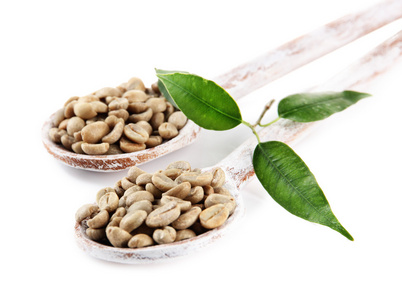 绿色咖啡豆的木质勺子和叶子上白色隔离