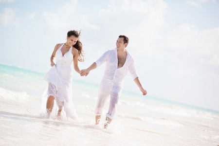 新婚夫妇在一个热带海滩上运行