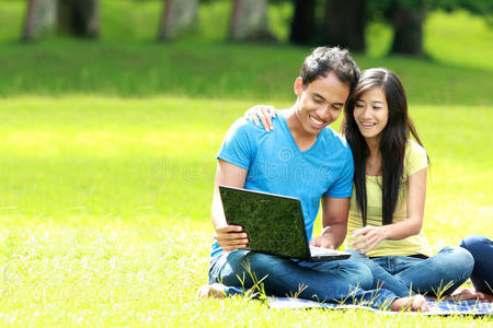 快乐的年轻夫妇在户外使用笔记本电脑
