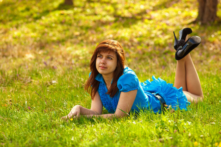 年轻的黑发女人躺在大自然绿色草在蓝光