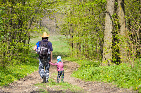 父亲和儿子一起走在春天森林路径