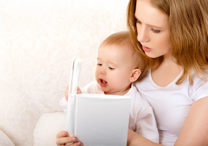 读一本书在沙发上的小宝宝的母亲