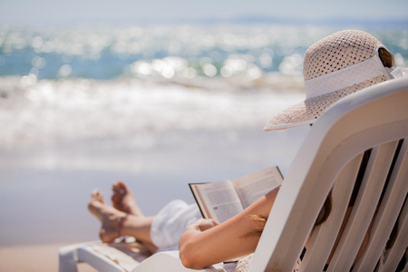 读一本书在海滩上的美丽女人