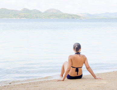 年轻漂亮的女人正坐在海边的沙滩上