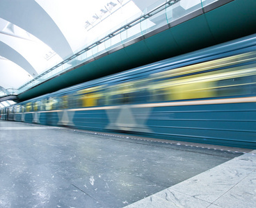 透视宽角度查看现代光蓝色照明和宽敞公共地铁大理石车站与快速模糊痕迹的消失交通运行中的列车