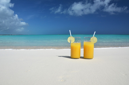 两杯橙汁在沙滩上