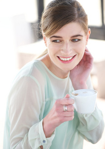 一个年轻的女人微笑，享受一杯咖啡的肖像