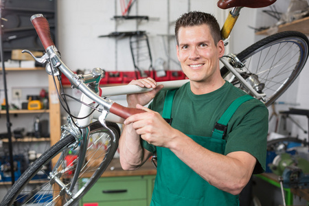 自行车修理工携带一辆自行车在车间微笑