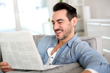 男人在家里放松与报纸图片