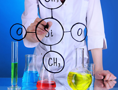 化学家女人在蓝色背景上的玻璃上写公式