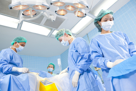 几个外科医生，在其工作期间围绕在手术台上的病人