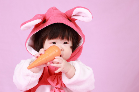 婴儿穿着复活节兔子耳朵与胡萝卜