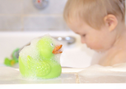 绿色浴鸭和沐浴在背景中的男孩