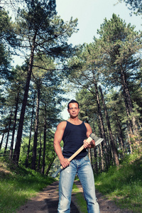 黑色衬衫和斧头在森林里的肌肉的男人