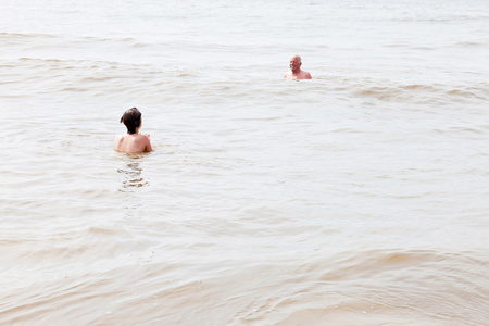 和爷爷在海中游泳的年轻男孩。享受海浪