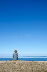 坐在海岸边的女人的垂直图像，蓝色和c
