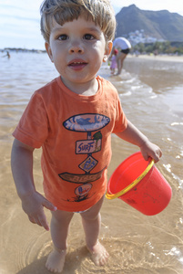 用红桶在海滩上玩的小孩