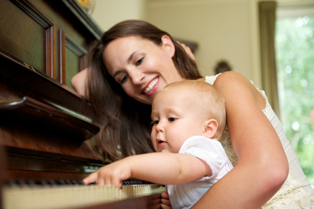 母亲微笑作为孩子弹钢琴
