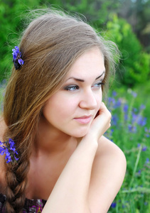一个漂亮的年轻女人在紫罗兰花户外的肖像