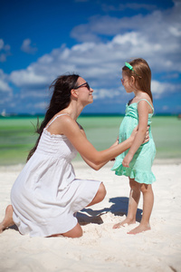 年轻的母亲和她可爱的女儿异国海滩上有乐趣