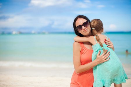 年轻漂亮的妈妈和她可爱的小女儿在热带海滩
