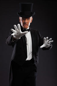 魔术师使神秘的手势。戴着帽子和黑色西装