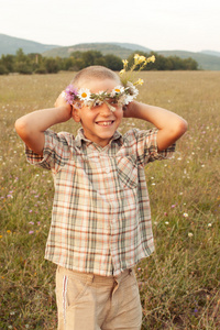 在秋天的阳光照射草甸字段中微笑的男孩