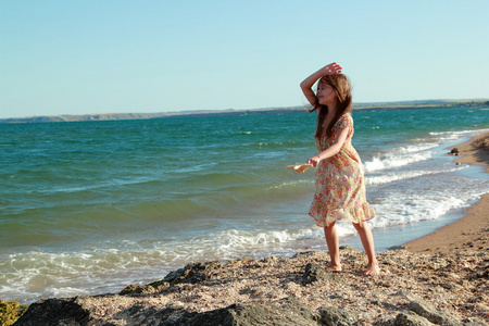 漂亮开朗微笑的小女孩在阳光明媚的夏日的海滩上跳舞