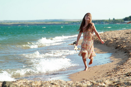 可爱的女孩与一个美丽的笑容，打赤脚在海滩上水