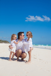 年轻爸爸和他可爱的女儿，在白色的沙滩上很开心