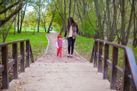 年轻的母亲和她的小女儿在秋天公园散步