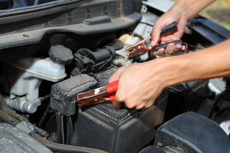 汽车修理工使用电池跳线电缆，电池充电