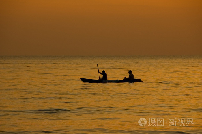 两个男人在一艘船在日落