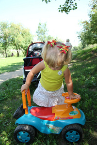 小女孩在公园里，户外驾驶她的玩具车