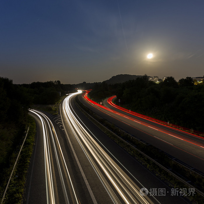 长时间曝光高速公路巡航车轻小道条纹的光速公路月亮多云