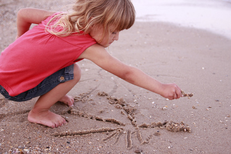 小女孩绘制太阳在沙子上海滩